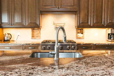 Example of a large classic l-shaped ceramic tile eat-in kitchen design in Toronto with an undermount sink, raised-panel cabinets, brown cabinets, granite countertops, beige backsplash, stone tile backsplash, stainless steel appliances and an island