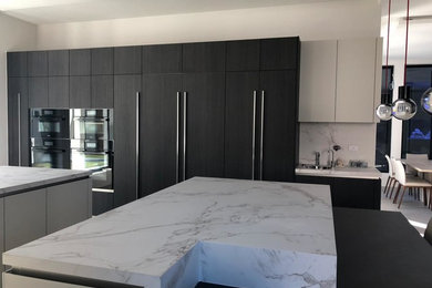 Inspiration for a huge contemporary ceramic tile and gray floor eat-in kitchen remodel in Houston with an undermount sink, flat-panel cabinets, dark wood cabinets, quartz countertops, white backsplash, stone slab backsplash, black appliances, two islands and white countertops
