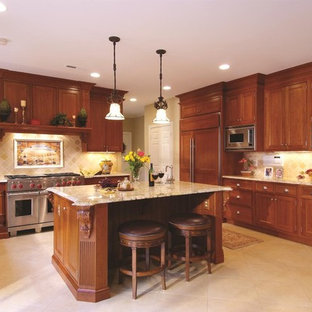 Foto de cocina en U, clásica, con armarios con paneles empotrados, puertas de armario de madera oscura, salpicadero beige, electrodomésticos con paneles y salpicadero de piedra caliza