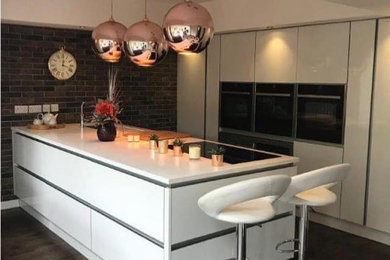 Design ideas for a modern enclosed kitchen in West Midlands with quartz worktops, white worktops, an integrated sink, white cabinets, integrated appliances and an island.