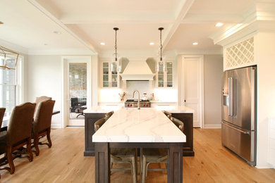 Inspiration for a large transitional l-shaped medium tone wood floor eat-in kitchen remodel in Minneapolis with shaker cabinets, white cabinets, stainless steel appliances, an island and white countertops