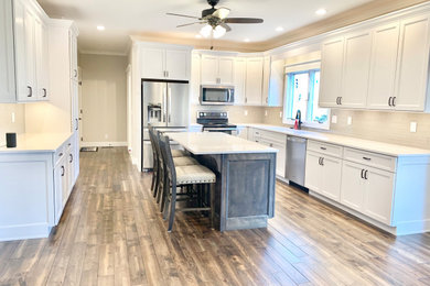 Open concept kitchen - large transitional l-shaped gray floor open concept kitchen idea in Other with an undermount sink, flat-panel cabinets, white cabinets, quartz countertops, beige backsplash, glass tile backsplash, stainless steel appliances, an island and beige countertops