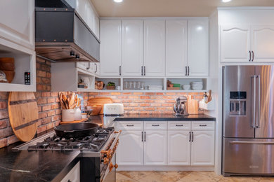 Example of a mid-sized tuscan single-wall eat-in kitchen design in Sacramento with shaker cabinets, white cabinets, soapstone countertops, red backsplash, brick backsplash, stainless steel appliances, an island and black countertops