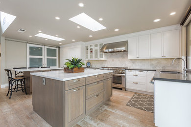 Large traditional l-shaped kitchen/diner in Other with a submerged sink, shaker cabinets, white cabinets, engineered stone countertops, white splashback, stainless steel appliances, light hardwood flooring, multiple islands and multi-coloured floors.