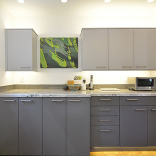 Mid-sized modern open concept kitchen designs - Example of a mid-sized minimalist galley cork floor and brown floor open concept kitchen design in San Luis Obispo with an undermount sink, flat-panel cabinets, gray cabinets, quartz countertops, gray backsplash, glass tile backsplash, stainless steel appliances, an island and gray countertops