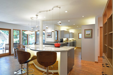 Example of a mid-sized minimalist galley cork floor and brown floor open concept kitchen design in San Luis Obispo with an undermount sink, flat-panel cabinets, gray cabinets, quartz countertops, gray backsplash, glass tile backsplash, stainless steel appliances, an island and gray countertops