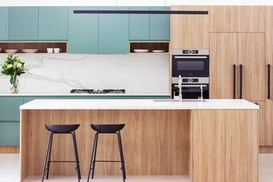 シドニーにある高級な中くらいなコンテンポラリースタイルのおしゃれなキッチン (ダブルシンク、淡色木目調キャビネット、クオーツストーンカウンター、白いキッチンパネル、黒い調理設備、ラミネートの床、ベージュの床、白いキッチンカウンター) の写真