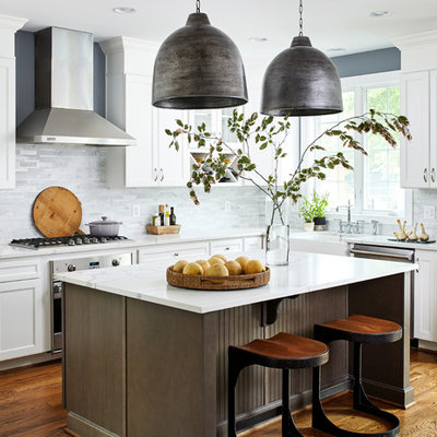 Kitchen - mid-sized transitional l-shaped medium tone wood floor and brown floor kitchen idea in DC Metro with a farmhouse sink, recessed-panel cabinets, white cabinets, gray backsplash, stainless steel appliances, an island and white countertops