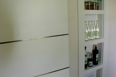Example of a small trendy l-shaped porcelain tile kitchen design in Boston with a single-bowl sink, flat-panel cabinets, white cabinets, quartz countertops, gray backsplash, ceramic backsplash, stainless steel appliances and no island
