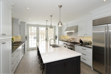 モダンスタイルのおしゃれなキッチン (一体型シンク、黄色いキャビネット、珪岩カウンター、白いキッチンパネル、シルバーの調理設備、茶色い床、黒いキッチンカウンター) の写真