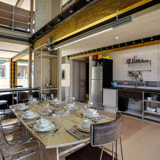 Idée de décoration pour une grand cuisine ouverte linéaire urbaine avec un évier encastré, un placard sans porte, une façade en inox, un électroménager en acier inoxydable, un sol en bois clair et aucun îlot.