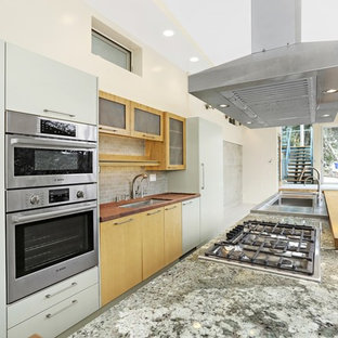 Inspiration for a mid-sized modern galley open plan kitchen in Los Angeles with an integrated sink, flat-panel cabinets, light wood cabinets, granite benchtops, beige splashback, porcelain splashback, stainless steel appliances and with island.