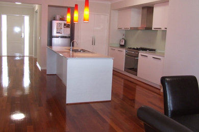 Foto de cocina contemporánea grande abierta con una isla, suelo de madera clara y suelo marrón