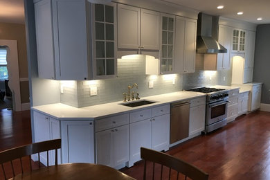 Inspiration for a mid-sized transitional galley medium tone wood floor and brown floor eat-in kitchen remodel in Boston with an undermount sink, shaker cabinets, white cabinets, marble countertops, gray backsplash, glass tile backsplash, stainless steel appliances and no island