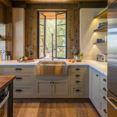 Mid-sized mountain style l-shaped medium tone wood floor kitchen photo in San Francisco with a farmhouse sink, gray cabinets, marble countertops, stainless steel appliances and window backsplash