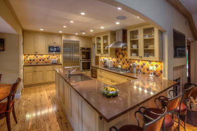 Mid-sized elegant u-shaped light wood floor open concept kitchen photo in San Francisco with an undermount sink, shaker cabinets, yellow cabinets, quartzite countertops, multicolored backsplash, ceramic backsplash, stainless steel appliances and a peninsula