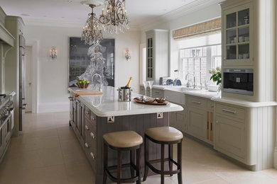 Large traditional galley kitchen/diner in Other with raised-panel cabinets, grey cabinets, quartz worktops, an island, a belfast sink, white splashback, stone slab splashback, stainless steel appliances and limestone flooring.