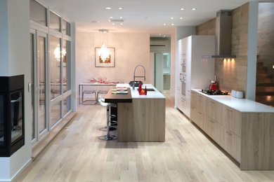 Eat-in kitchen - mid-sized modern single-wall light wood floor and beige floor eat-in kitchen idea in Seattle with an undermount sink, flat-panel cabinets, white cabinets, quartz countertops, brown backsplash, an island, white countertops and paneled appliances