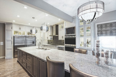 Transitional light wood floor kitchen photo in Edmonton with a double-bowl sink, recessed-panel cabinets, white cabinets, quartzite countertops, brown backsplash, stainless steel appliances and an island