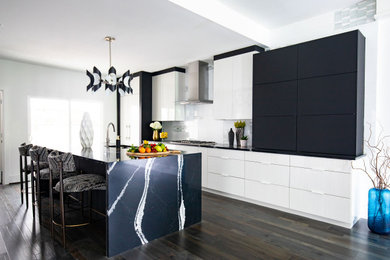 Inspiration for a contemporary galley kitchen in Houston with flat-panel cabinets, white cabinets, granite worktops, white splashback, stainless steel appliances, medium hardwood flooring, an island, multi-coloured floors and black worktops.