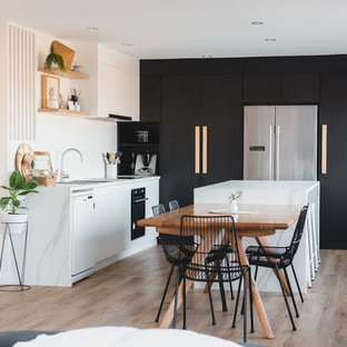 Contemporary l-shaped eat-in kitchen in Hobart with an undermount sink, flat-panel cabinets, black cabinets, white splashback, stainless steel appliances, medium hardwood floors, with island, brown floor and white benchtop.