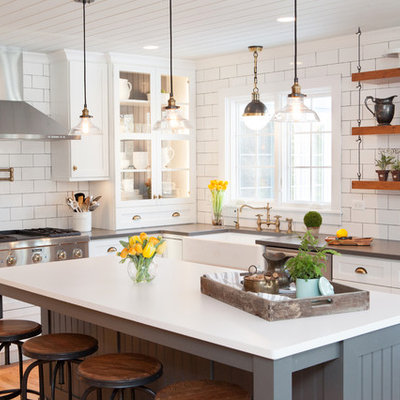 Example of a mid-sized country u-shaped medium tone wood floor kitchen design in Chicago with a farmhouse sink, recessed-panel cabinets, white cabinets, quartz countertops, multicolored backsplash, subway tile backsplash, stainless steel appliances and an island
