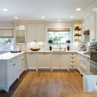 Design ideas for a mid-sized shabby-chic style u-shaped open plan kitchen in Vancouver with an undermount sink, shaker cabinets, white cabinets, quartz benchtops, white splashback, mosaic tile splashback, panelled appliances, medium hardwood floors and no island.