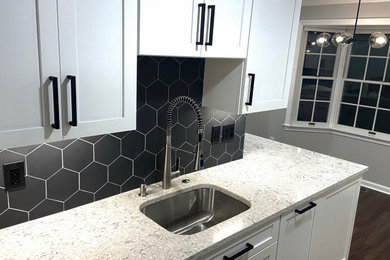 Example of a mid-sized trendy galley laminate floor and brown floor eat-in kitchen design in Boston with a drop-in sink, shaker cabinets, white cabinets, quartz countertops, black backsplash, ceramic backsplash, stainless steel appliances, no island and beige countertops