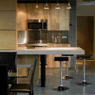 Mid-sized minimalist galley concrete floor eat-in kitchen photo in Phoenix with an undermount sink, flat-panel cabinets, light wood cabinets, concrete countertops, metallic backsplash, metal backsplash, stainless steel appliances and an island