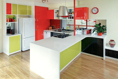 Photo of a large eclectic l-shaped open plan kitchen in Perth with a built-in sink, flat-panel cabinets, engineered stone countertops, glass sheet splashback, black appliances, medium hardwood flooring, a breakfast bar and white worktops.