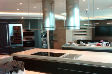 Diseño de cocina comedor minimalista grande con armarios con paneles lisos, puertas de armario marrones, encimera de cuarzo compacto y electrodomésticos de acero inoxidable