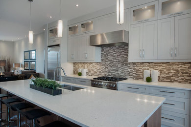 Design ideas for a large contemporary u-shaped open plan kitchen in Calgary with a submerged sink, shaker cabinets, white cabinets, engineered stone countertops, multi-coloured splashback, matchstick tiled splashback, stainless steel appliances, dark hardwood flooring and an island.