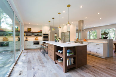 Inspiration for a large 1950s single-wall light wood floor and brown floor eat-in kitchen remodel in Other with an undermount sink, flat-panel cabinets, medium tone wood cabinets, quartz countertops, white backsplash, stainless steel appliances and two islands