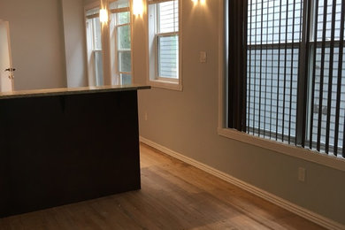 Example of a mid-sized ornate single-wall light wood floor and beige floor eat-in kitchen design in Other with an undermount sink, flat-panel cabinets, brown cabinets, granite countertops, white appliances, an island and beige countertops