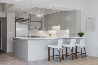 Enclosed kitchen - mid-sized contemporary u-shaped light wood floor and beige floor enclosed kitchen idea in Boston with flat-panel cabinets, gray cabinets, stainless steel appliances, an island, an undermount sink, quartz countertops and white countertops