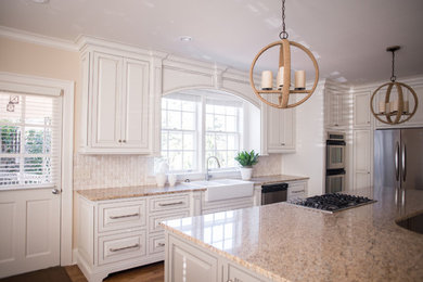 Example of a large classic l-shaped light wood floor eat-in kitchen design in Atlanta with a farmhouse sink, raised-panel cabinets, white cabinets, granite countertops, beige backsplash, mosaic tile backsplash, stainless steel appliances and an island