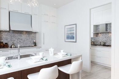 Enclosed kitchen - mid-sized contemporary galley porcelain tile enclosed kitchen idea in Vancouver with an undermount sink, flat-panel cabinets, white cabinets, quartz countertops, gray backsplash, mosaic tile backsplash, black appliances and a peninsula