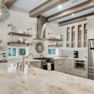 Mid-sized coastal enclosed kitchen designs - Mid-sized beach style u-shaped light wood floor and brown floor enclosed kitchen photo in Miami with a farmhouse sink, shaker cabinets, white cabinets, quartzite countertops, white backsplash, wood backsplash, stainless steel appliances, a peninsula and white countertops