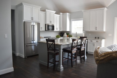 Inspiration for a mid-sized timeless l-shaped dark wood floor and brown floor open concept kitchen remodel in Other with a farmhouse sink, shaker cabinets, white cabinets, granite countertops, stainless steel appliances and an island