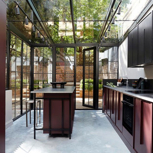 Design ideas for a traditional kitchen in London with a single-bowl sink, black cabinets, black appliances, concrete flooring, an island, grey floors and grey worktops.