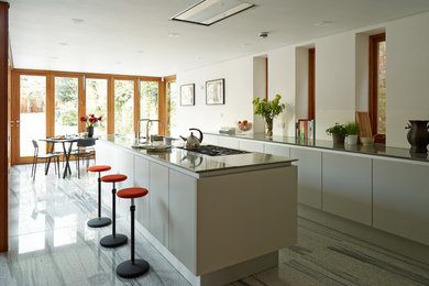 Foto på ett stort funkis linjärt kök och matrum, med en dubbel diskho, släta luckor, grå skåp, bänkskiva i koppar, rostfria vitvaror, travertin golv och en köksö