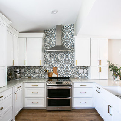 Example of a mid-sized transitional u-shaped vinyl floor and brown floor eat-in kitchen design in Denver with a farmhouse sink, shaker cabinets, white cabinets, quartz countertops, multicolored backsplash, cement tile backsplash, stainless steel appliances, a peninsula and gray countertops