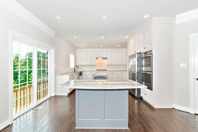 ワシントンD.C.にある広いトランジショナルスタイルのおしゃれなキッチン (シェーカースタイル扉のキャビネット、白いキャビネット、御影石カウンター、シルバーの調理設備、濃色無垢フローリング) の写真