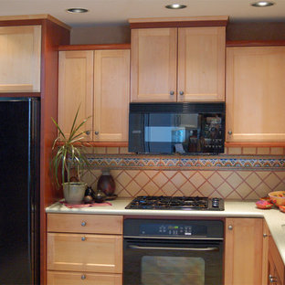 Small l-shaped separate kitchen in San Luis Obispo with an integrated sink, recessed-panel cabinets, light wood cabinets, solid surface benchtops, yellow splashback, ceramic splashback, black appliances, travertine floors and green benchtop.