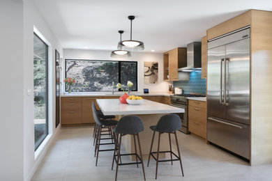 ロサンゼルスにあるコンテンポラリースタイルのおしゃれなキッチン (アンダーカウンターシンク、フラットパネル扉のキャビネット、中間色木目調キャビネット、青いキッチンパネル、シルバーの調理設備、グレーの床、白いキッチンカウンター) の写真