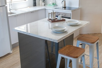 Esempio di una piccola cucina minimalista con lavello da incasso, ante lisce, ante bianche, top in laminato, paraspruzzi bianco, elettrodomestici in acciaio inossidabile e pavimento in linoleum