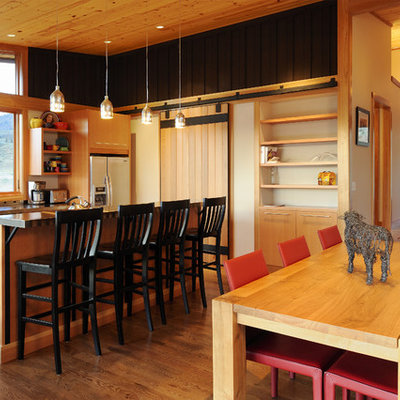 Example of a mid-sized transitional galley medium tone wood floor and brown floor eat-in kitchen design in Seattle with medium tone wood cabinets, a double-bowl sink, flat-panel cabinets, solid surface countertops, stainless steel appliances and an island
