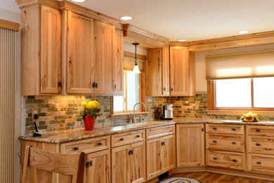 Large rural u-shaped kitchen/diner in Minneapolis with an integrated sink, shaker cabinets, light wood cabinets, laminate countertops, green splashback, stone tiled splashback, white appliances, laminate floors, brown floors and multicoloured worktops.