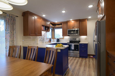 Small eclectic u-shaped kitchen/diner in Minneapolis with a submerged sink, shaker cabinets, blue cabinets, laminate countertops, beige splashback, travertine splashback, stainless steel appliances, laminate floors, brown floors and beige worktops.