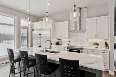 Example of a mid-sized transitional l-shaped laminate floor and brown floor eat-in kitchen design in Other with an undermount sink, shaker cabinets, white cabinets, quartz countertops, white backsplash, porcelain backsplash, stainless steel appliances, an island and white countertops